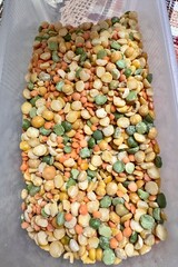 Mixture of yellow and green peas, lentils in plastic white container. Close-up