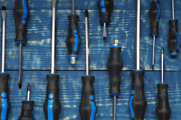 Set of screwdrivers on blue wooden table, flat lay