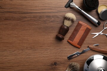 Naklejka premium Moustache and beard styling tools on wooden background, flat lay. Space for text