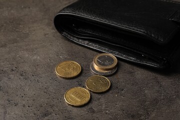 Poverty. Black wallet and coins on grey table, closeup - obrazy, fototapety, plakaty
