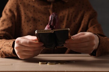 Poverty. Woman with empty wallet and coins at wooden table, closeup - obrazy, fototapety, plakaty
