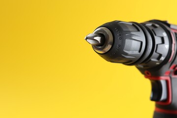 Modern electric screwdriver on yellow background, closeup. Space for text