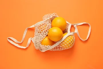 Foto op Canvas String bag with fresh oranges on color background, top view © New Africa