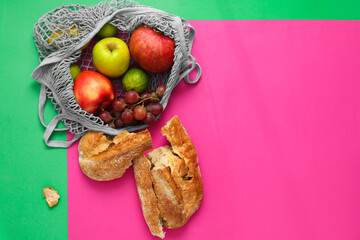 String bag with fresh fruits and pieces of bread on color background, flat lay. Space for text