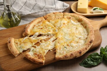 Delicious cut cheese pizza and ingredients on wooden table