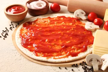 Fotobehang Pizza base smeared with tomato sauce, peppercorns and products on light textured table, closeup © New Africa