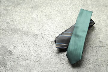 Two neckties on grey textured background, top view. Space for text