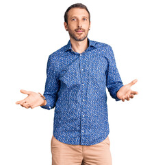 Young handsome man wearing casual clothes clueless and confused expression with arms and hands...