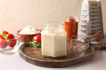Pizza dough starter in glass jar, products and whisk on gray table