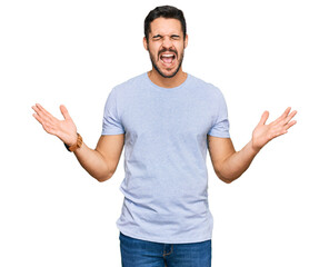 Naklejka premium Young hispanic man wearing casual clothes celebrating mad and crazy for success with arms raised and closed eyes screaming excited. winner concept