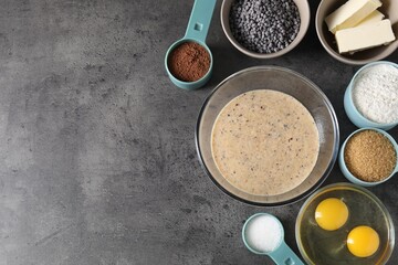Raw dough with chocolate chips in bowl and ingredients on grey table, flat lay. Space for text