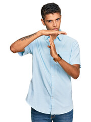 Young handsome african american man wearing casual clothes doing time out gesture with hands,...