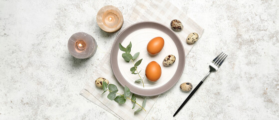 Table setting with Easter eggs, fork and burning candles on white grunge background