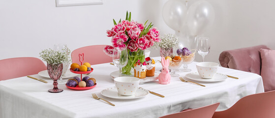 Stylish table setting with beautiful tulips for Easter celebration in room