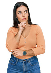 Young hispanic woman wearing casual clothes with hand on chin thinking about question, pensive...