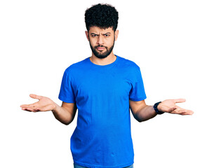 Young arab man with beard wearing casual blue t shirt clueless and confused with open arms, no idea concept.