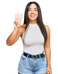 Young beautiful hispanic girl wearing casual clothes showing and pointing up with fingers number three while smiling confident and happy.