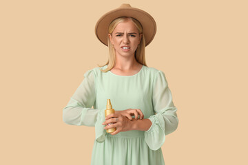 Young woman with mosquito repellent on beige background