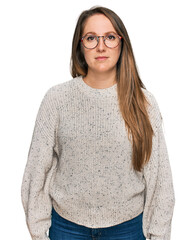 Young blonde woman wearing casual sweater and glasses relaxed with serious expression on face. simple and natural looking at the camera.