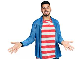 Young hispanic man with beard wearing casual denim jacket smiling cheerful with open arms as friendly welcome, positive and confident greetings