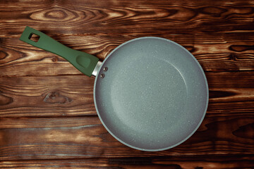 Frying Pan With Green Handle on Wooden Table