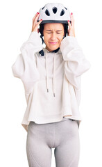 Beautiful brunette young woman wearing bike helmet and sporty clothes suffering from headache desperate and stressed because pain and migraine. hands on head.