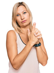 Naklejka premium Middle age caucasian woman wearing casual clothes holding symbolic gun with hand gesture, playing killing shooting weapons, angry face