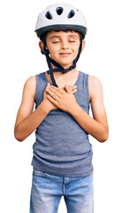 Little cute boy kid wearing bike helmet smiling with hands on chest with closed eyes and grateful gesture on face. health concept.