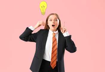 Funny shocked businesswoman with paper light bulb as symbol of idea on pink background