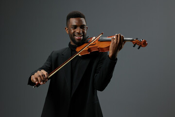 Talented violinist playing passionately in elegant black suit on neutral gray background