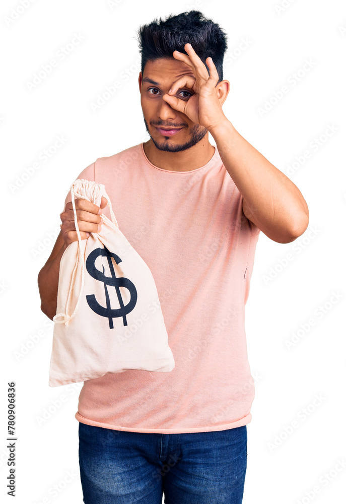 Wall mural handsome latin american young man holding money bag with dollar symbol smiling happy doing ok sign w