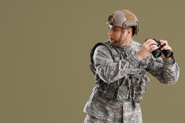 Male soldier in uniform with binoculars looking around on green background