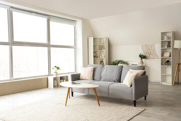 Interior of light living room with grey sofa and laptop on table - obrazy, fototapety, plakaty