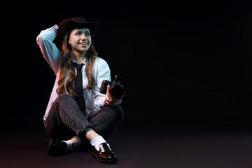 Portrait of stylish female photographer with modern camera on black background