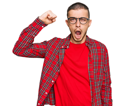 Hispanic young man wearing casual clothes angry and mad raising fist frustrated and furious while shouting with anger. rage and aggressive concept.