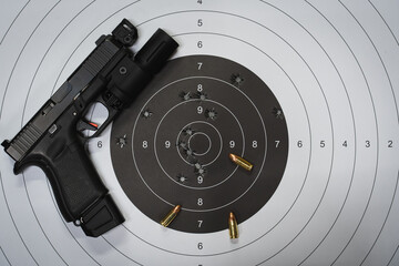 Tactical pistol and paper target with bullet holes in the center.