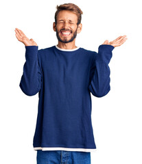 Handsome blond man with beard wearing casual sweater celebrating mad and crazy for success with...