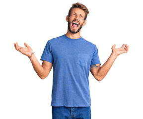 Handsome blond man with beard wearing casual clothes crazy and mad shouting and yelling with...