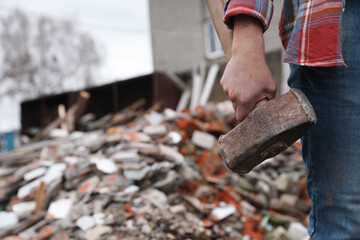 Man with sledgehammer near pile of broken stones outdoors, closeup. Space for text