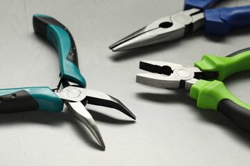 Different pliers on grey textured table, closeup