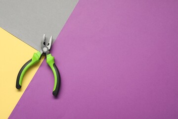 Combination pliers on color background, top view. Space for text