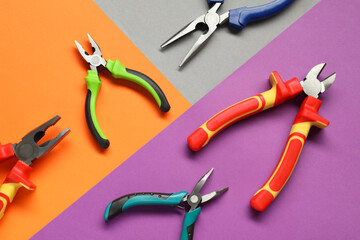 Different pliers on color background, flat lay