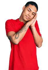 Young hispanic man wearing casual red t shirt sleeping tired dreaming and posing with hands together while smiling with closed eyes.