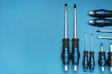 Set of screwdrivers on blue background, flat lay. Space for text