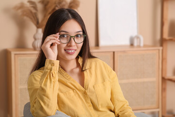 Beautiful young happy Asian woman with stylish eyeglasses at home