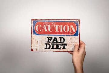 Foto op Plexiglas Fad Diet. Metal warning sign in a woman's hand on a white background © STOATPHOTO