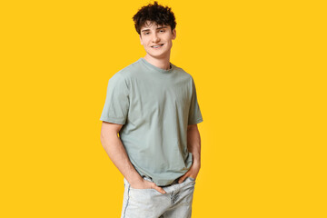 Handsome young man in stylish t-shirt on yellow background