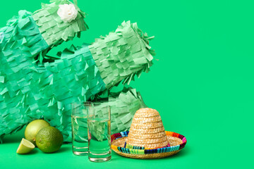 Mexican pinata, lime, sombrero hat,  bottle and shots of tequila on green background