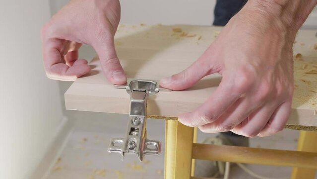 Carpenter man drilling round holes in a wooden chipboard plate for door hinge. Door furniture. Woodworking industry and furniture assembly concept 