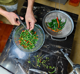 hands cutting chilies with scissors on a man is cutting or chopping chilies using scissors in the...